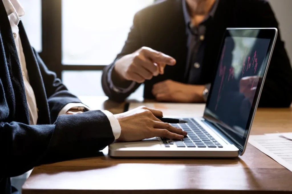 Advogados analisam gráfico no laptop, discutindo como otimizar campanhas Google Ads para advogados.