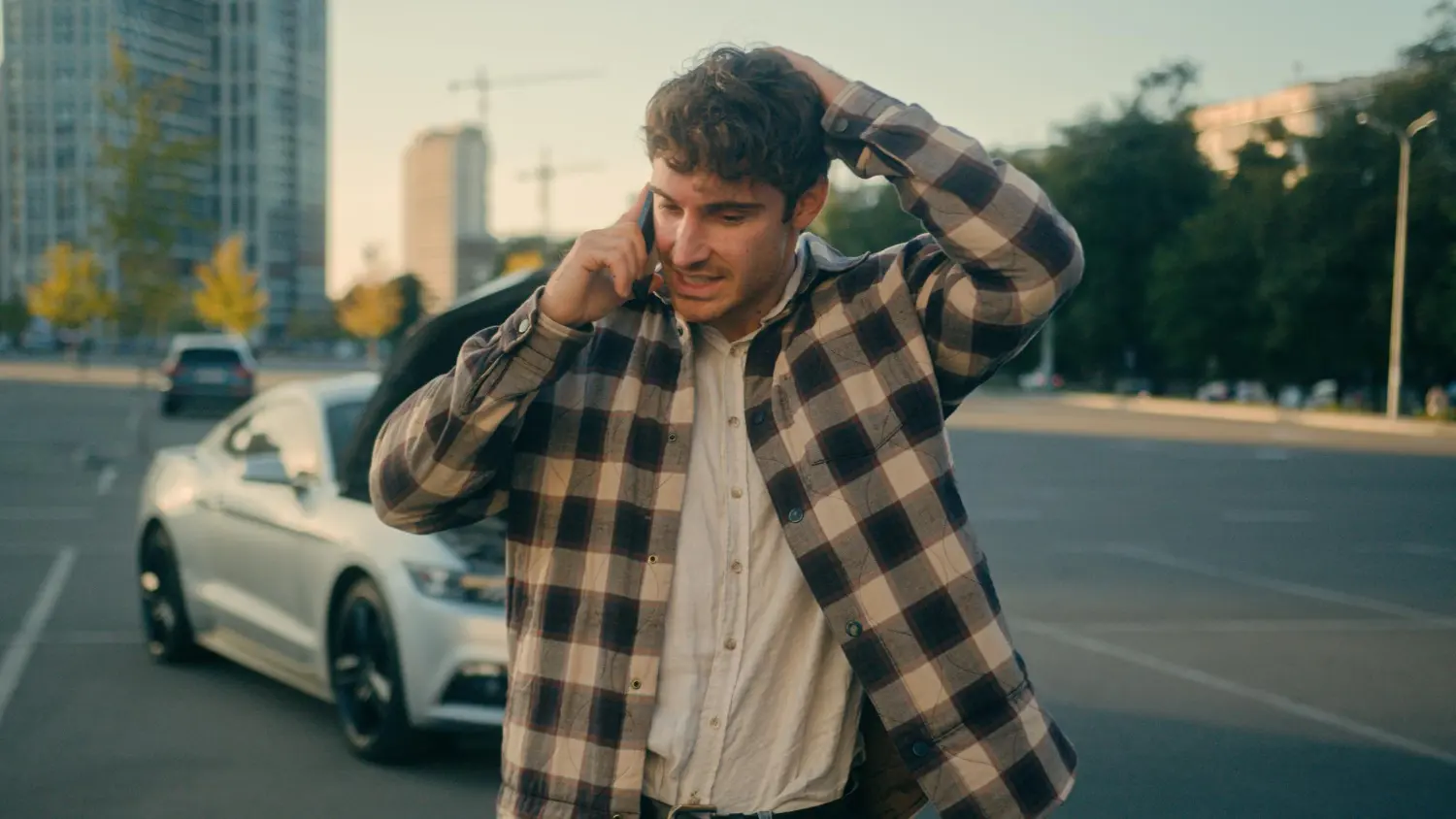 Homem preocupado ao telefone perto de carro com capô aberto, cliente desesperado por melhores palavras-chave para Google Ads.