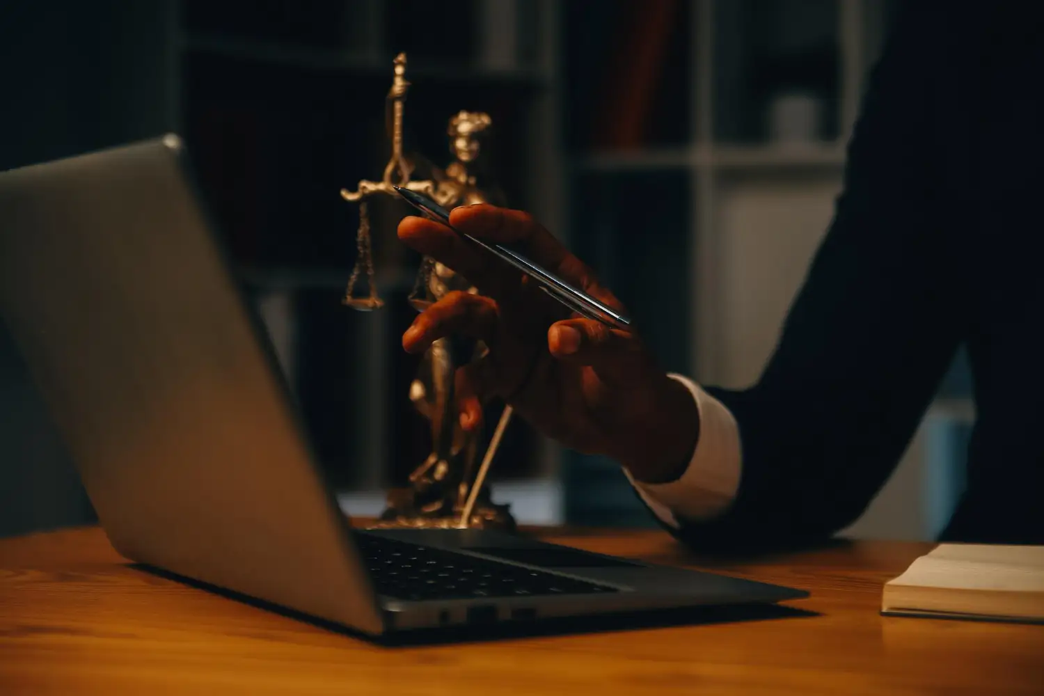 Advogado com estátua da justiça e laptop, pensando em como criar um site para advogado.