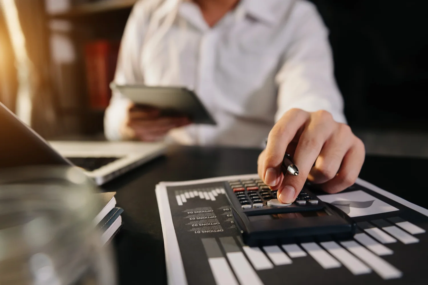 Homem usando calculadora e preparando orçamento para escolher agência de marketing para advogado.