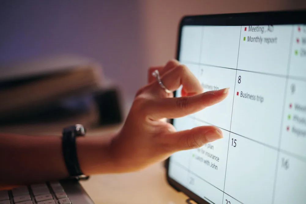 Mão aponta para calendário digital, planejando como escrever artigos para blog jurídico que convertem.