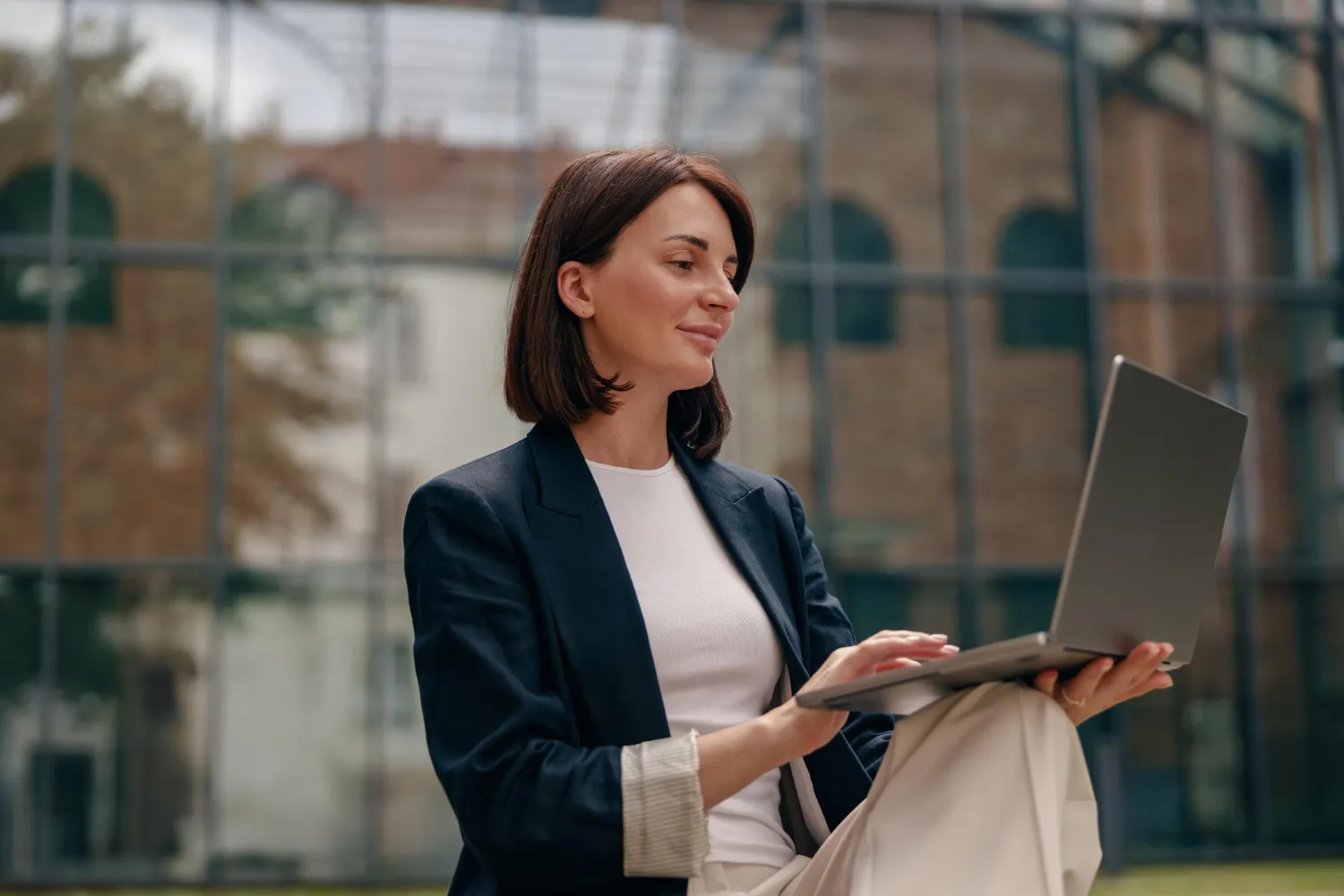 Mulher de blazer trabalhando no laptop, focada em marketing para advogados.