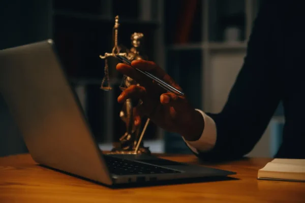 Advogado com estátua da justiça e laptop, pensando em como criar um site para advogado.