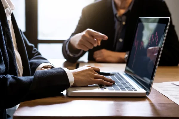 Advogados analisam gráfico no laptop, discutindo como otimizar campanhas Google Ads para advogados.