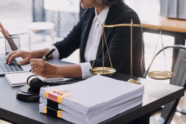 Advogado escrevendo em caderno com balança da justiça, buscando melhores palavras-chave para Google Ads advocacia trabalhista.